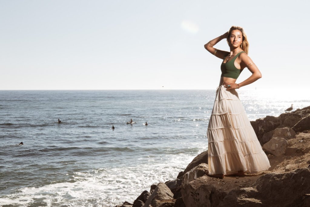 A model stands on a cliff overlooking the ocean.